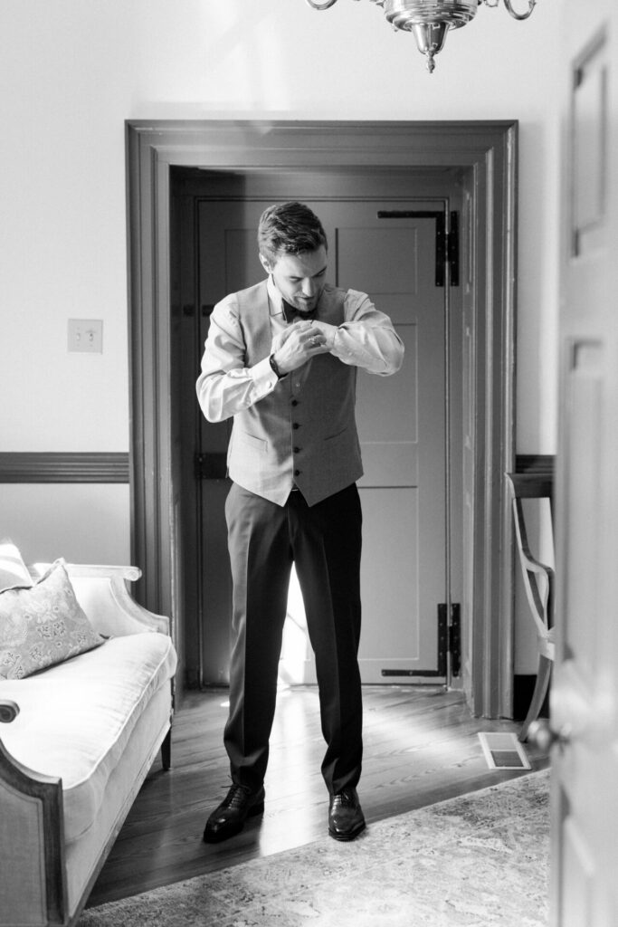 Black and white photo of groom putting on cufflinks Seven Springs wedding