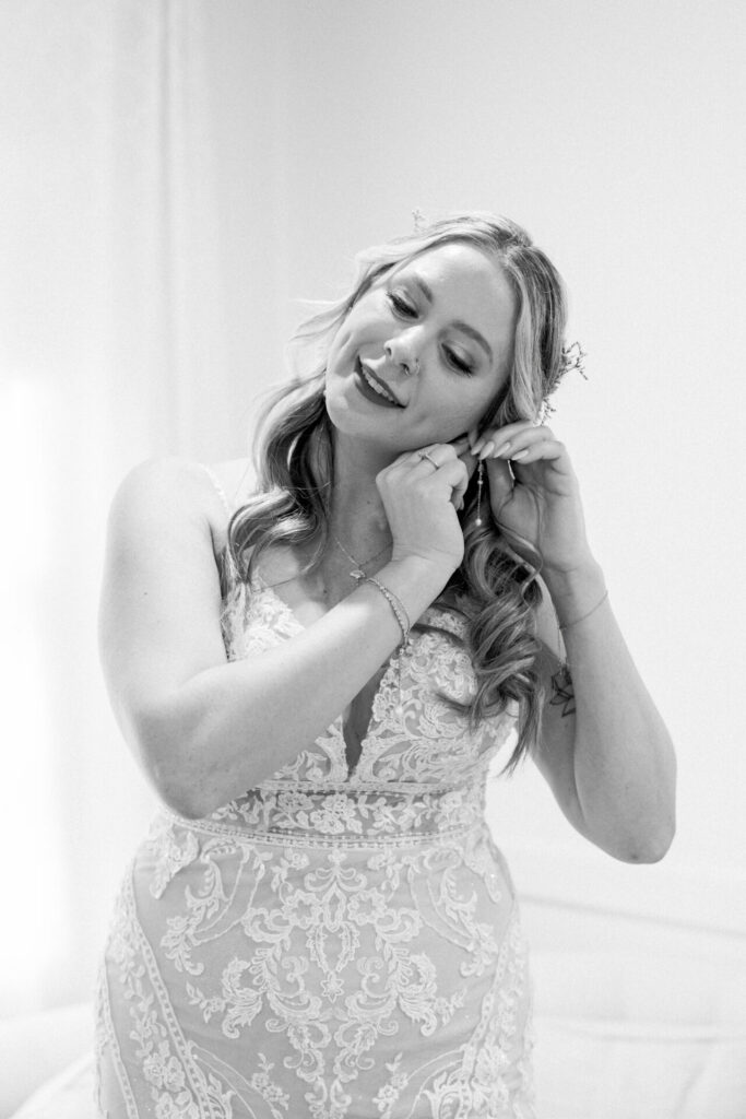 black and white photo of bride putting on earrings Seven Springs wedding Richmond Va